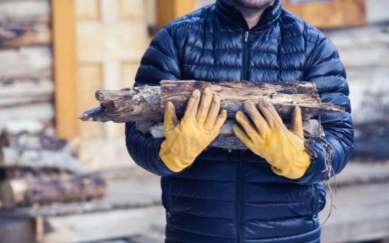 Man in down jacket carrying wood