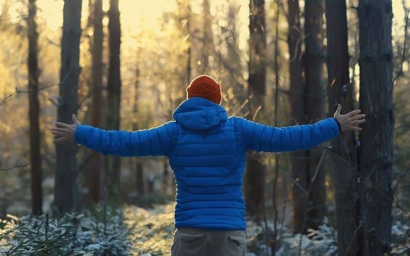 Man in down jacket holding his arms out