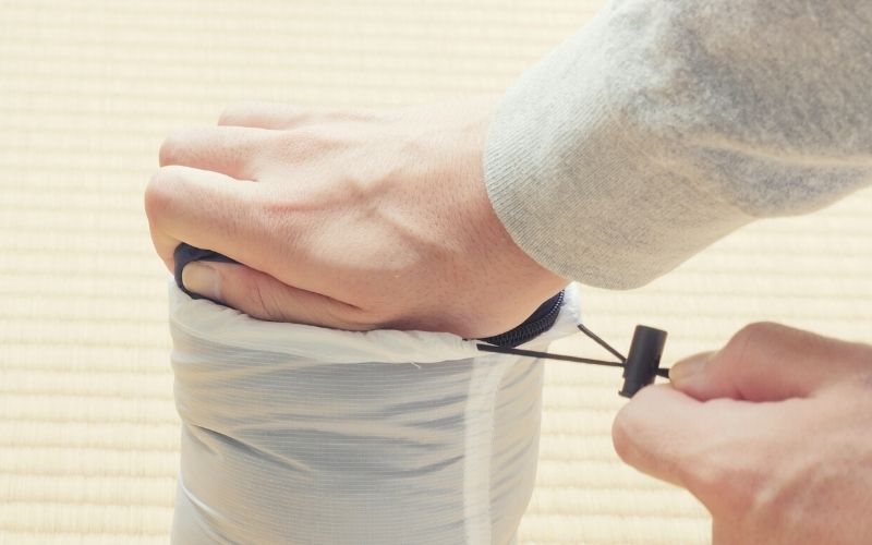 Person putting down jacket into stuff sack