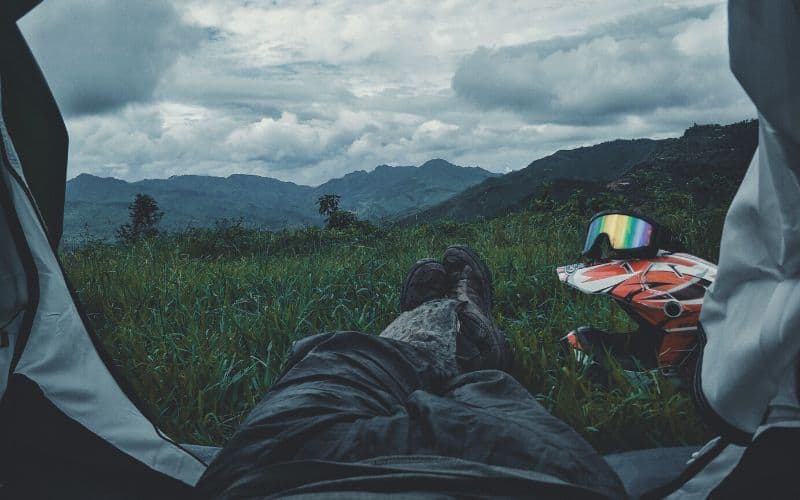 Campers legs sticking out of tent with views of mountains