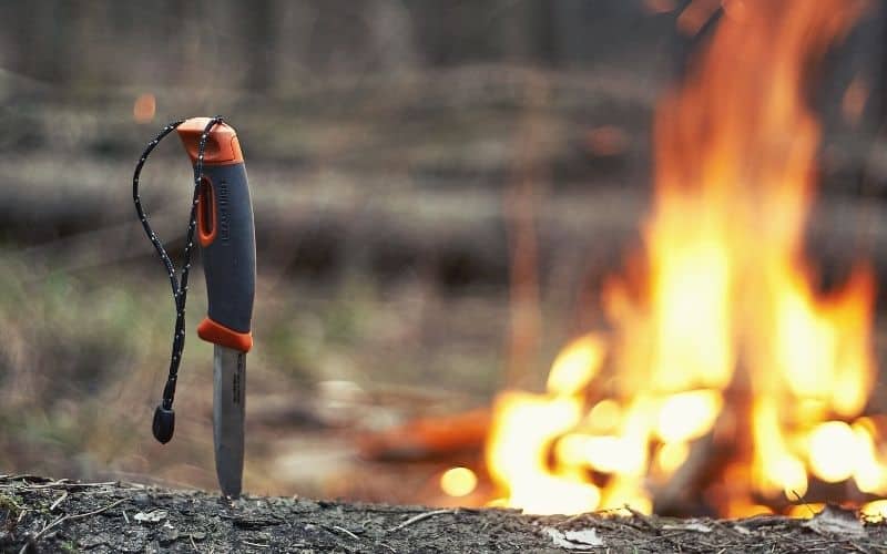 Camping knife standing up in front of a campfire