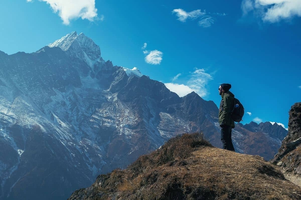 Man wearing backpack looking out over snowy mountain tops