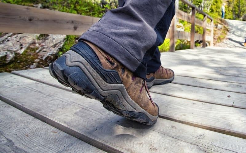 Person wearing hiking boots across wooden boardwalk