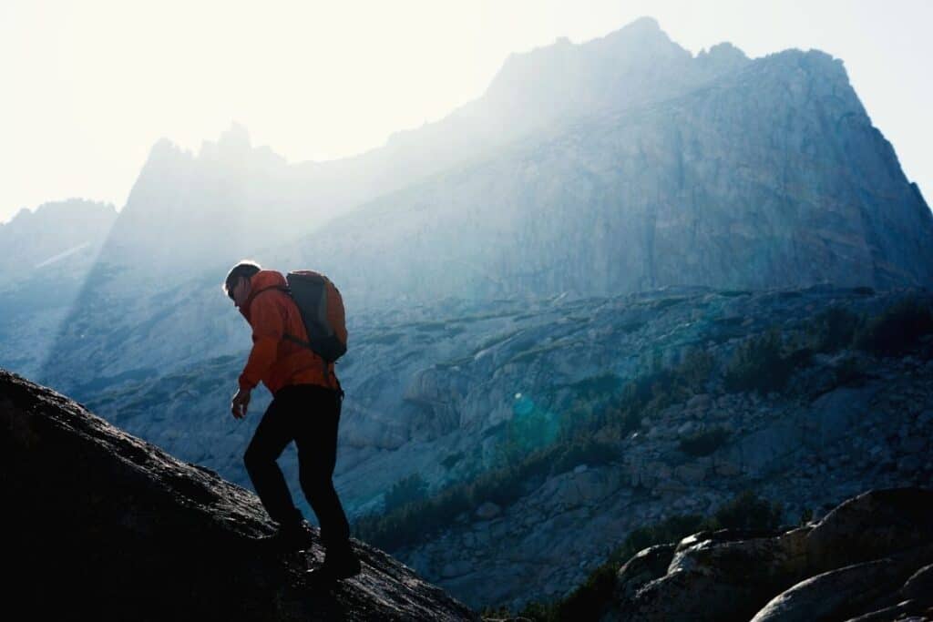 Hiker wearing backpack ascending a mountain