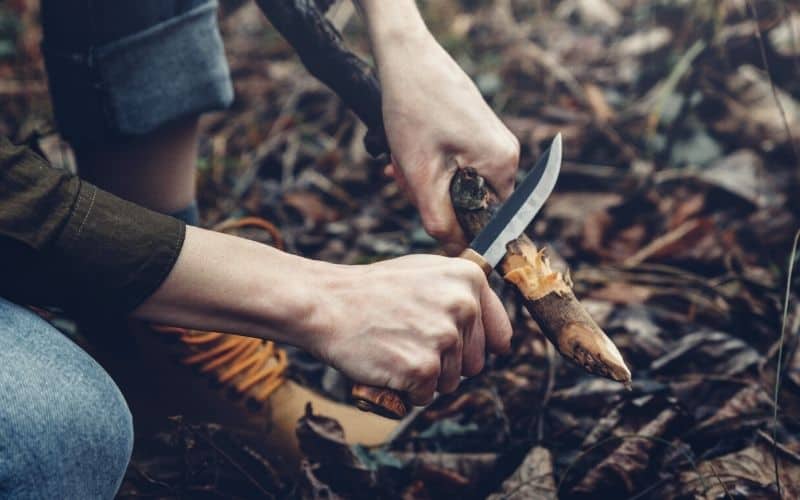 Woman using a drop point blade to whittle wood