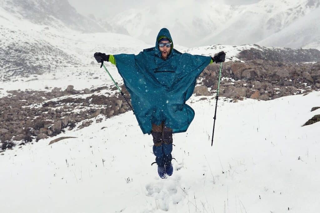 Man jumping in snow wearing a waterproof poncho
