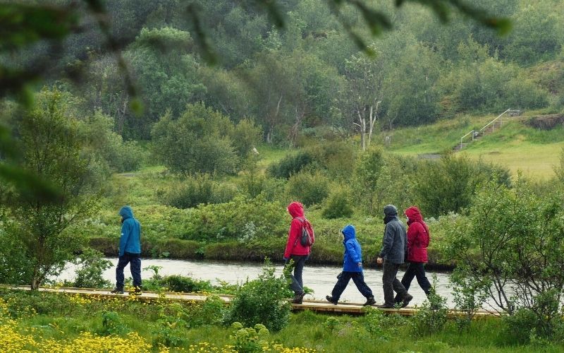 Group of hikers walking along a river wearing waterproof clothing