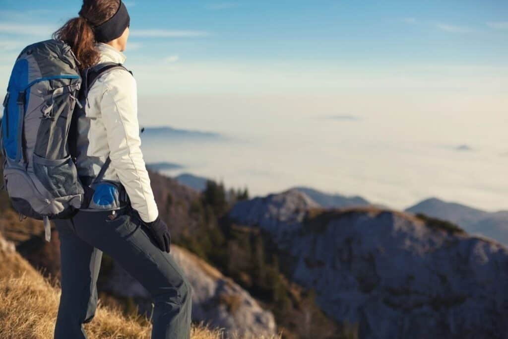 Hiker wearing backpack and looking out over mountians