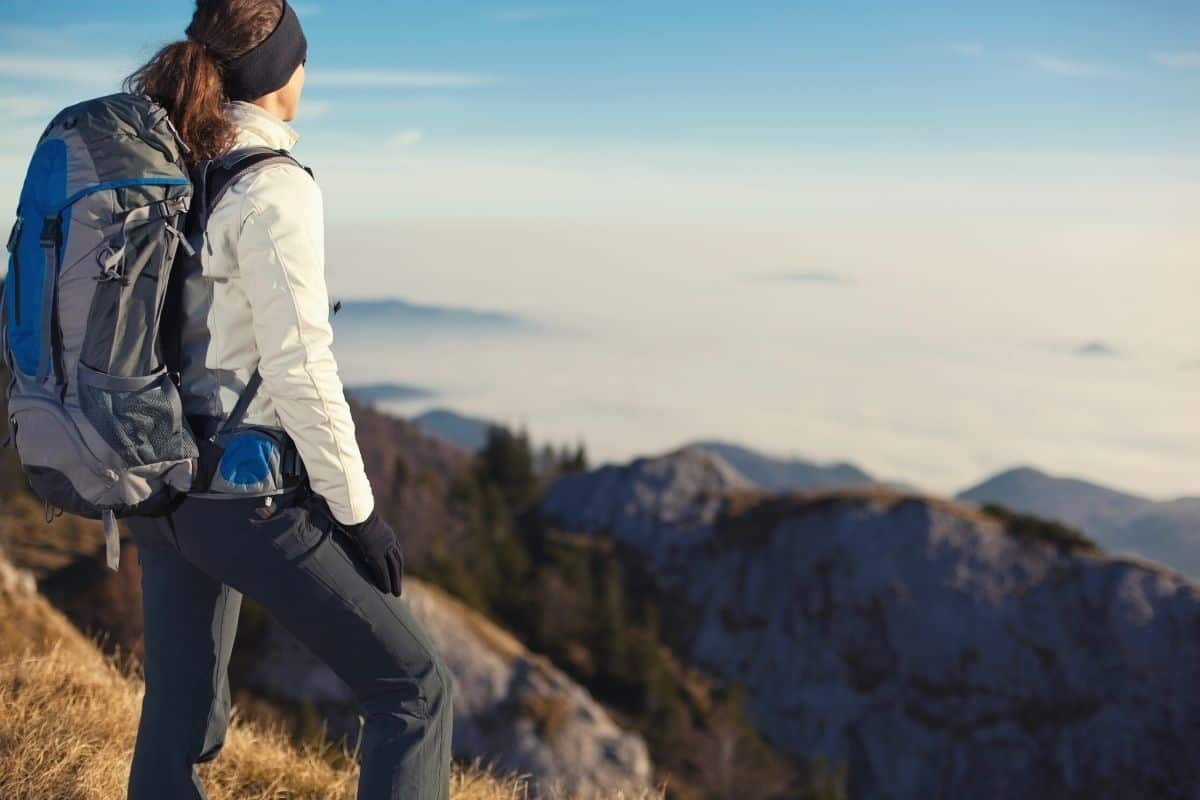 Hiker wearing backpack and looking out over mountians