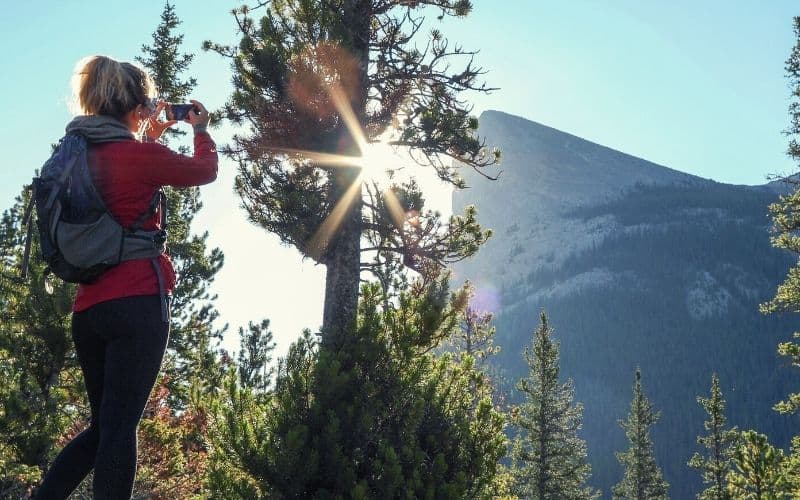 Woman using cell phone on hiking trail up mountains