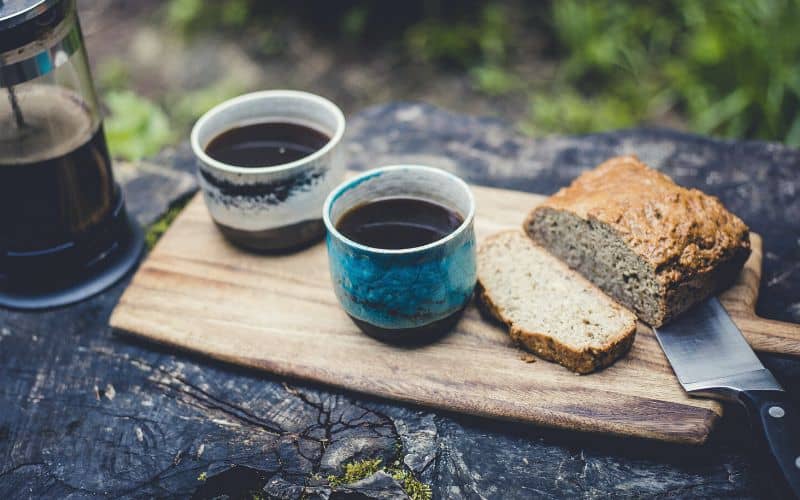 banana bread and coffee sitting on tree trunk