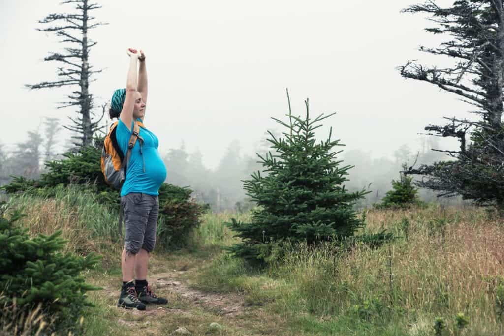 Pregnant woman hiking through forest