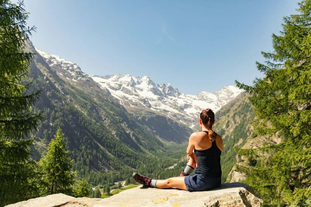 Woman sitting on cliff edge looking at mountains