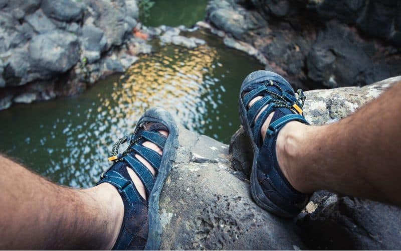 Man sitting high above pool of water wearing waterproof sandals