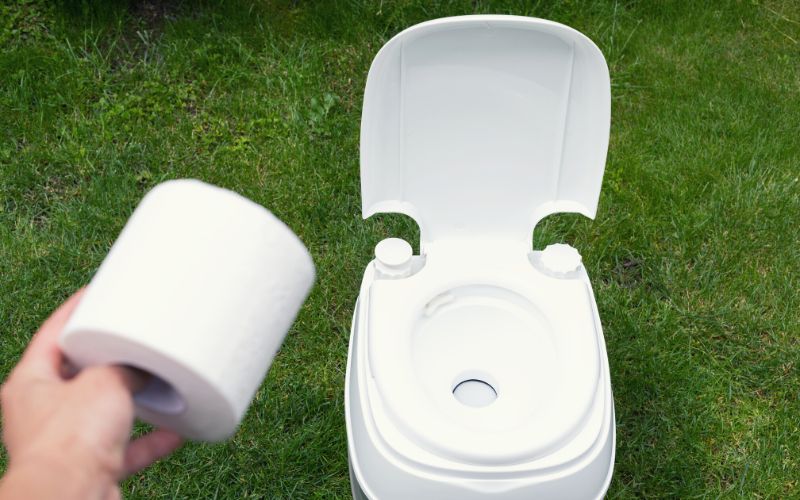 Portable toilet and man holding toilet roll