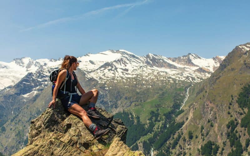 Woman sitting on rocks at top of mountain wearing shorts