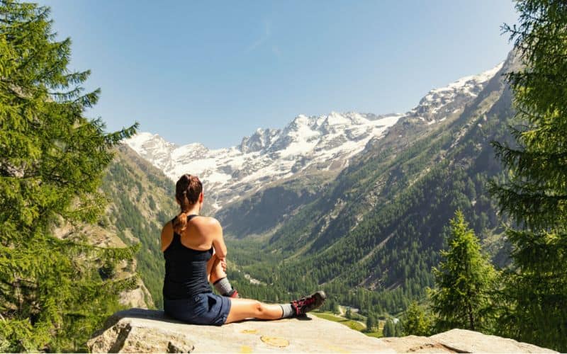 Woman in shorts sitting looking at mountains