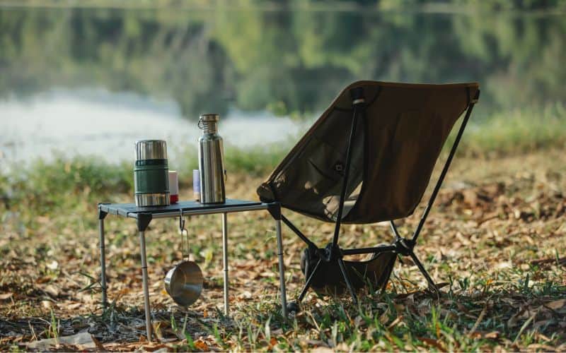 Backpacking chair and small side table in front of a lake