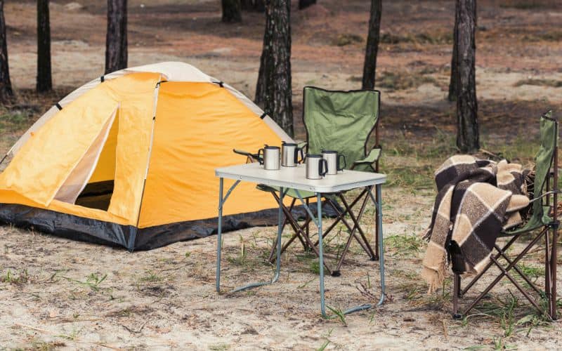 Camping table and chairs setup outside a tent