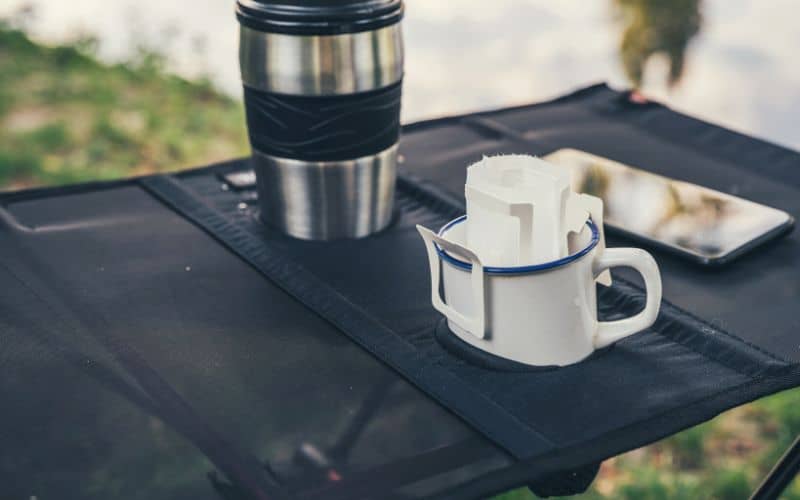 Camping table with fabric tabletop and integrated cup holders