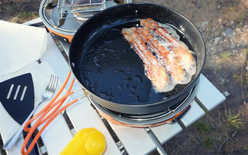 Frying bacon in a pan with foldable handles