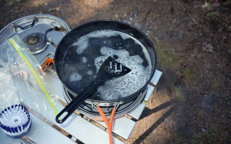 Frying pan filled with soapy water sitting on camping tabletop