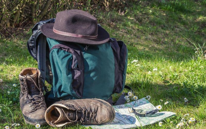 Hat sitting on top of backpack, boots, map and compass