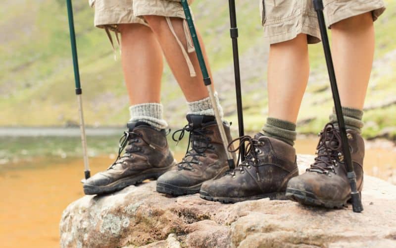Hikers feet holding telescopic hiking poles