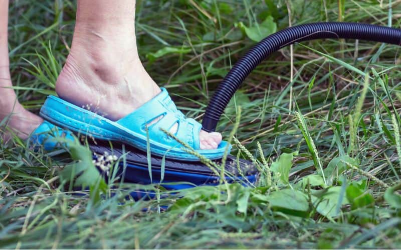 Person pumping a foot pump in the grass