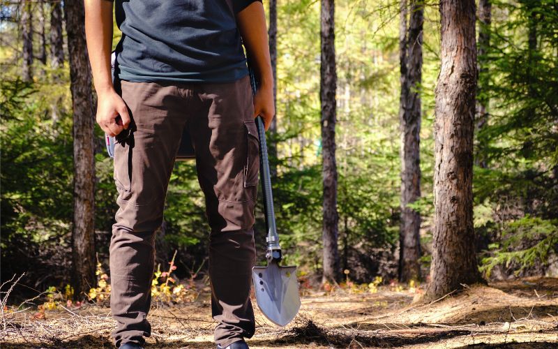 Man holding a shovel in the forest