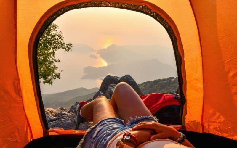 Hiker sticking legs out of tent wearing camp booties