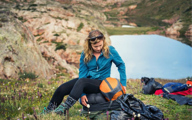 Camper packing compression sacks in front of water filled crater