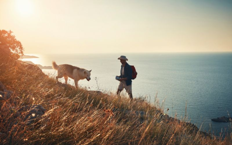 Man and dog hiking along coastline