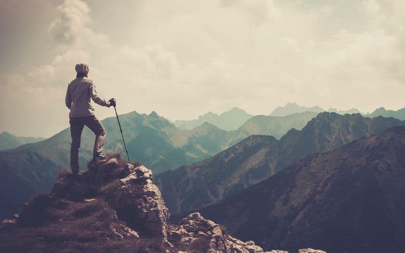 Hiker standing on mountaintop holding trekking pole