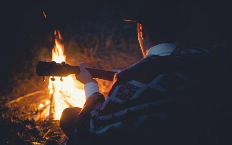 playing the guitar in front of camp fire