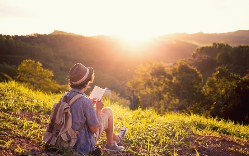 Man reading a book on a hilltop