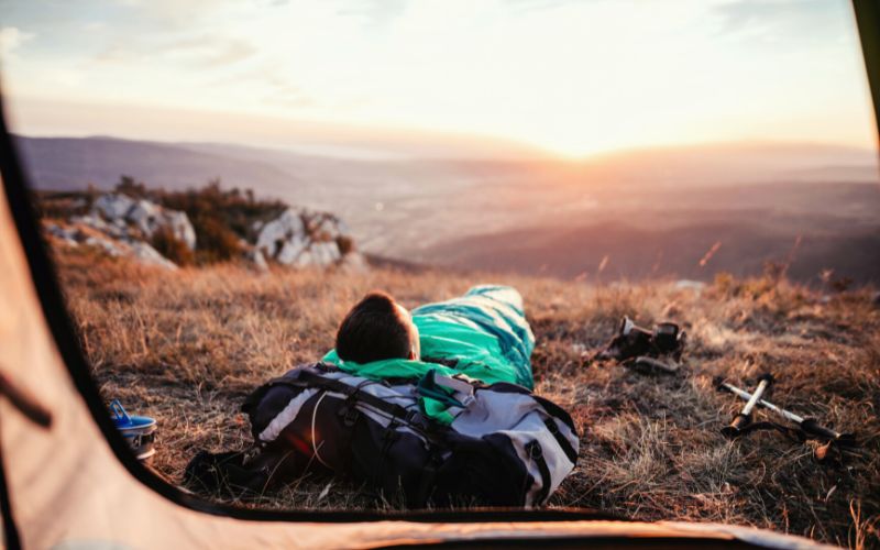 Man in sleeping bag outside of his tent