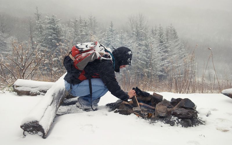 Man starting campfire in the snow
