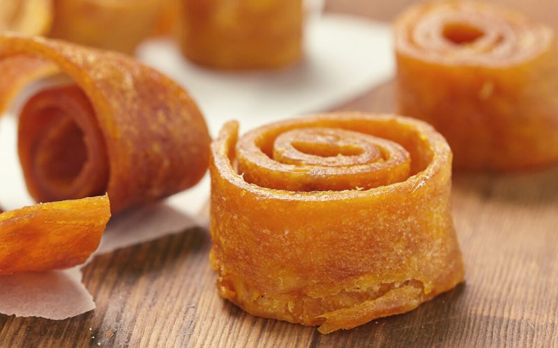 Mango fruit leather curled up on wooden surface