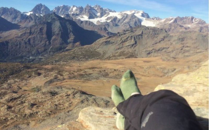 A pair of Ibex pants clad legs in front of the Alps