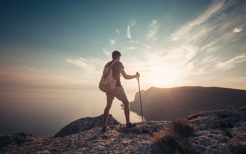 Man with walking stick on clifftop looking out over the view