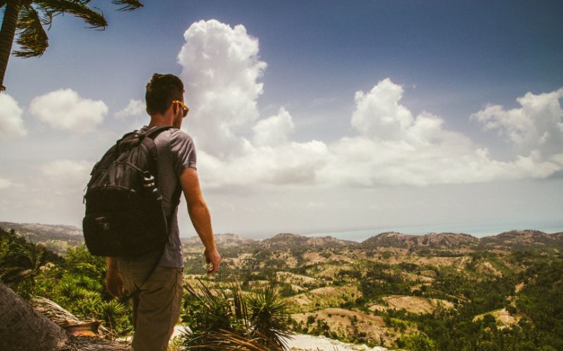 Man wearing backpack looking out over a desert landscape