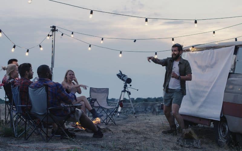 Adults playing charades outside their campervan