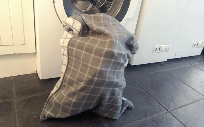 Backpack inside pillowcase in front of washing machine