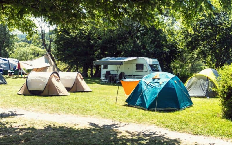 Busy campground with tents pitched and an RV parked
