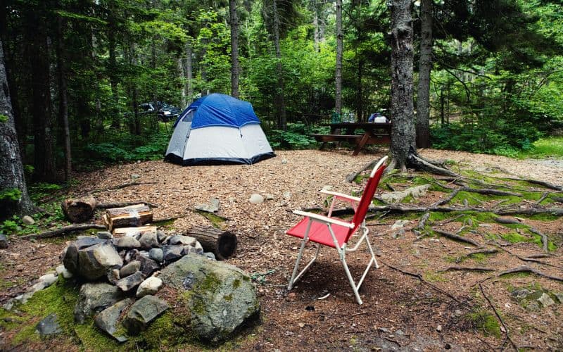 Camp chair sitting in front of a tent in the forest