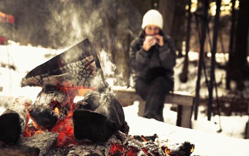 Camper sitting beside campfire in the snow