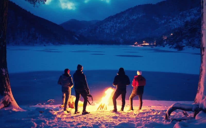 Campers standing around campfire in the snow