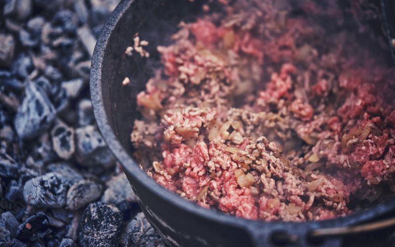 Cooking off mince and onion in a cast iron dutch oven over hot coals