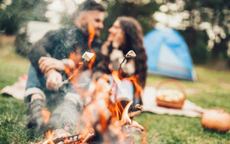 Couple toasting marshmallows over a campfire